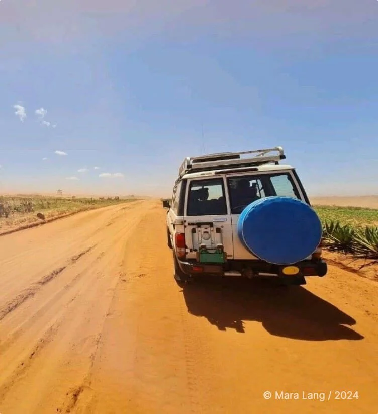 A field vehicle carrying water supplies down a dirt road